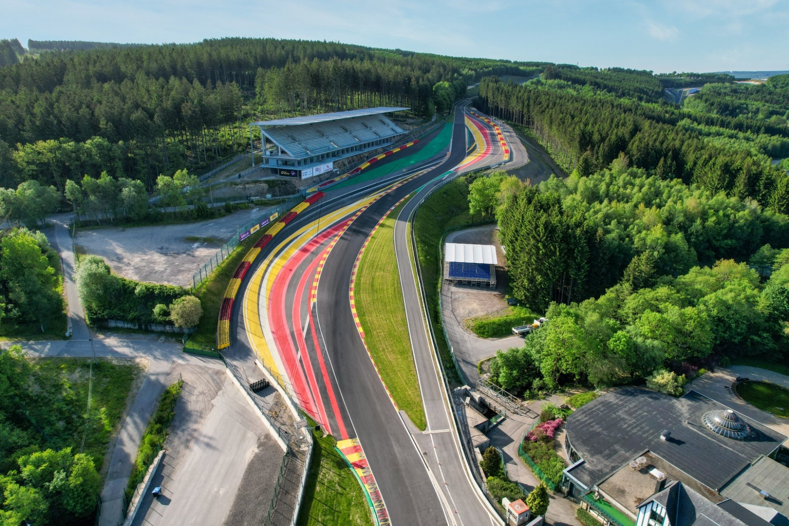 Vista aérea del circuito de Spa-Francorchamps entre los bosques de las Ardenas belgas, mostrando el desnivel del trazado y una tribuna junto a la pista